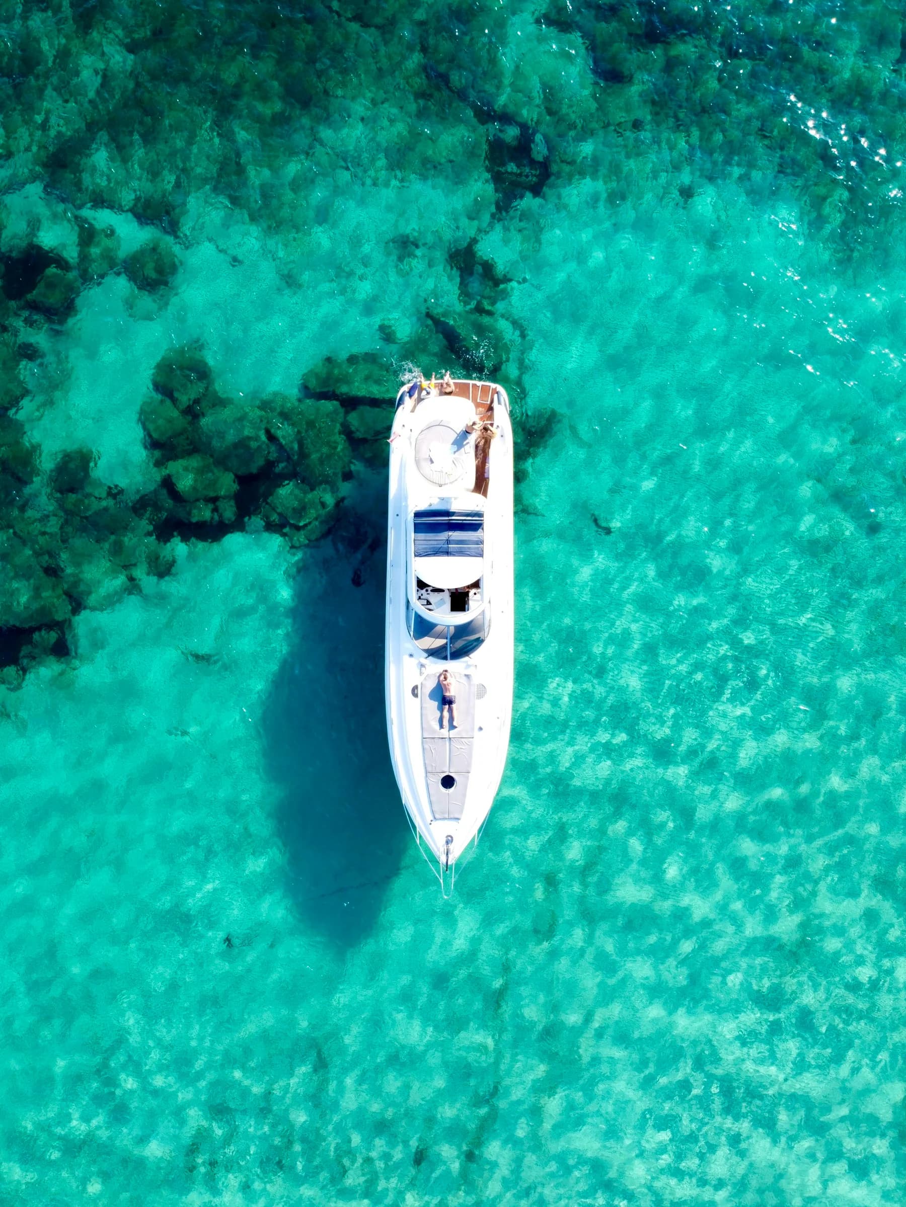 White motor yacht at anchor over crystal-clear turquoise water